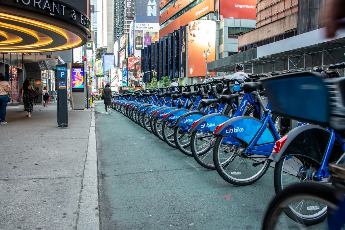 Citi Bikes neatly arranged on a busy street in Times Square, New York City.