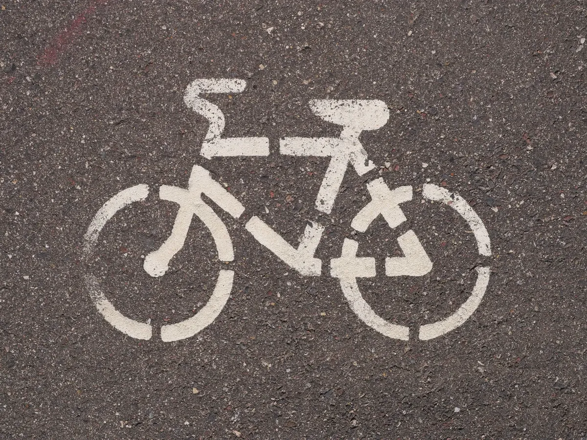 Close-up of a white bicycle lane marking on asphalt, showcasing urban cycling infrastructure.