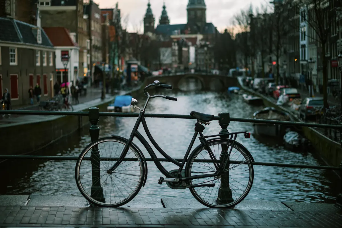 Classic bicycle parked on a bridge over Amsterdam's canals. Scenic and serene.
