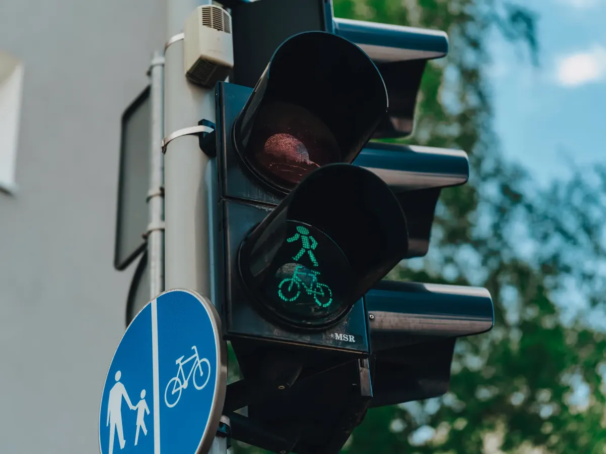 Close-up of a traffic light showing a green pedestrian and bicycle signal on an urban street.