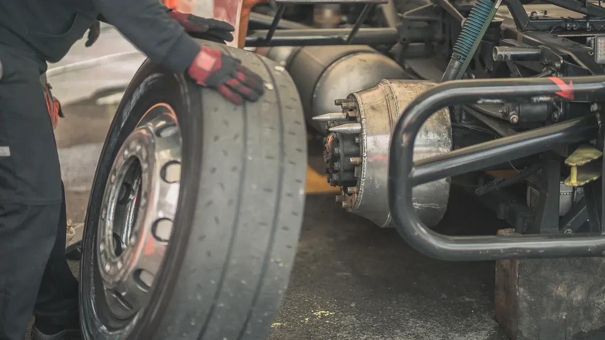 Mechanic working on replacing a tire in a professional automotive garage setting.