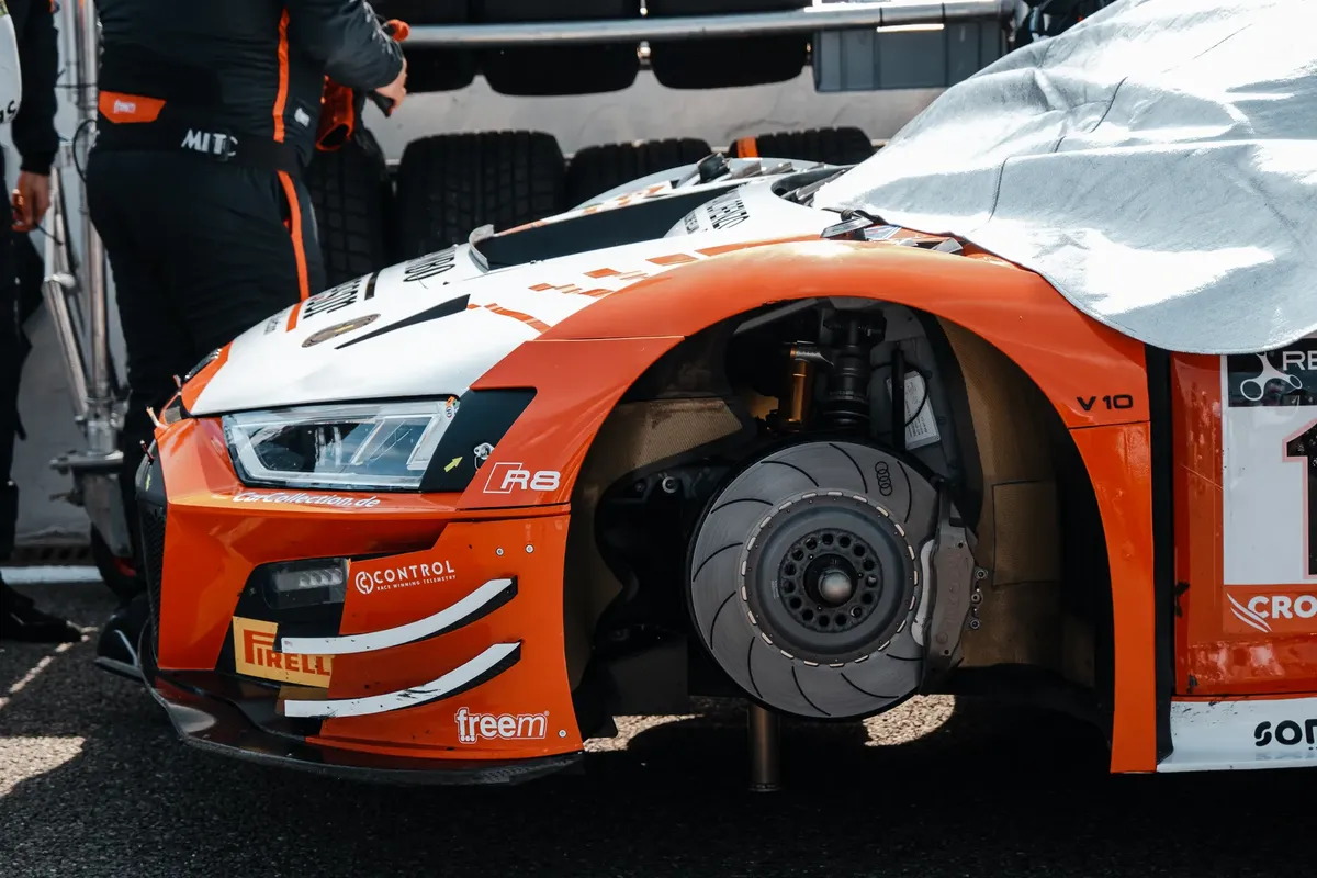 Close-up of a racing car wheel being repaired at a pit stop with mechanics working.