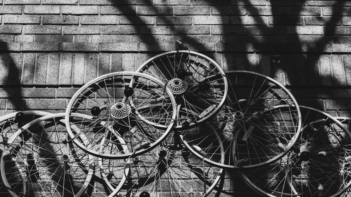 A striking black and white abstract photograph of multiple bicycle wheels against a brick wall in Somerville, Massachusetts.